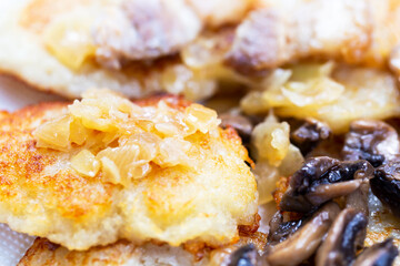 Freshly fried potato fritters with a roast of mushrooms, onions and lard