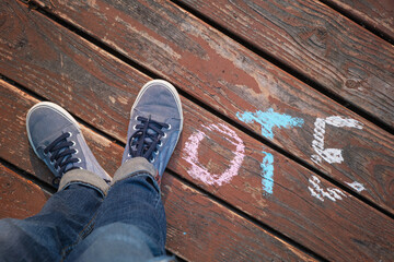 overhead view of legs and feet with shoes spelling out the word vote on a wooden deck