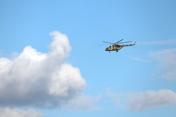 Fototapeta na wymiar Military helicopter Mi-8 (NATO codification: Hip) in flight on background of blue sky with white clouds 