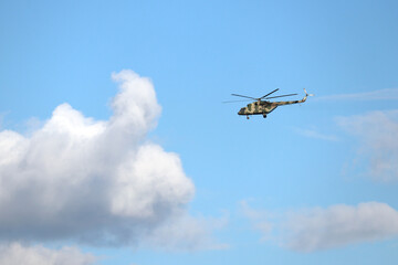 Military helicopter Mi-8 (NATO codification: Hip) in flight on background of blue sky with white clouds 