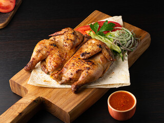 Grilled fried roast Chicken Tabaka and fresh vegetables on cutting board on wooden background