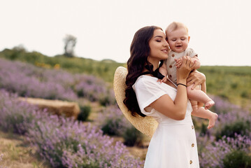 attractive young mother playing with her baby in a lavender field