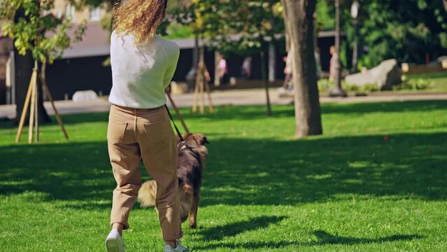 Young woman struggling to keep playful and active german shepherd dog on leash