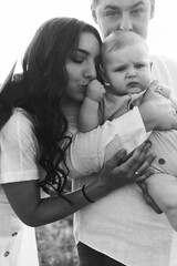 young beautiful family with baby in the field