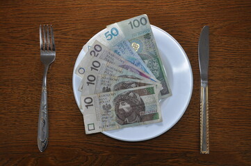 Polish Zloty lies on a white plate. Photo describes the problem of rising prices in the global...