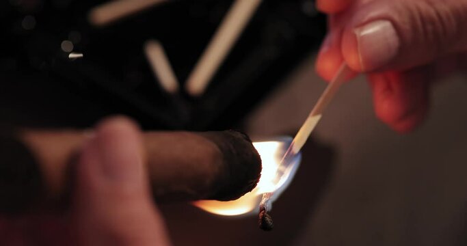 men's hands hold a burning match and set fire to a Cuban cigar. view from above. macro