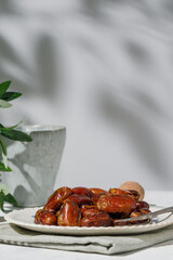 Dried dates and walnuts in a vintage plate on a white background . A sunny day.