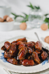 Dried dates and walnuts in a vintage plate on a white background . A sunny day.
