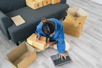 Fototapeta premium Starting small businesses SME owners female entrepreneurs Write the address on receipt box and check online orders to prepare to pack the boxes, sell to customers, sme business ideas online.