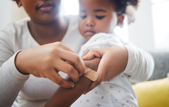 A mothers love is pure. Shot of a mother applying a bandaid to her daughters arm at home.