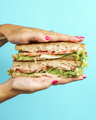Vertical shot of a female holding a tuna sandwich