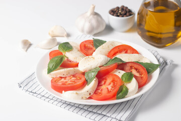 Delicious Italian caprese salad with sliced mozzarella, tomatoes, basil, pesto and garlic on background.