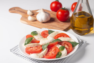 Delicious Italian caprese salad with sliced mozzarella, tomatoes, basil, pesto and garlic on background.