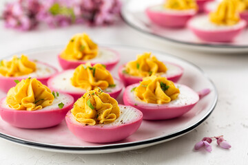 Stuffed Pink Deviled Eggs with  pepper and mayonnaise colored with beetroot. Easter food concept, spring flowers. Selective focus.