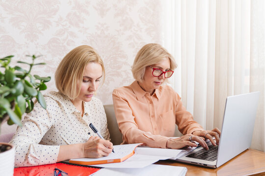 Mature business women discuss documents in the home office.