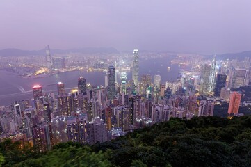Night scenery of Hong Kong viewed from top of Victoria Peak with city skyline of crowded skyscrapers along Victoria Harbour and Kowloon area across seaport ~ Beautiful cityscape of Hongkong at sunset