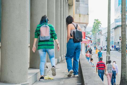 two girls walking through the city of Pereira-Colombia, trying not to step on the garbage in the streets.