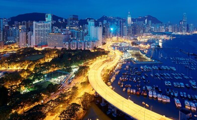Aerial scenery of Hong Kong in blue morning twilight, with view of crowded skyscrapers by Victoria Harbour, boats parking in Causeway Bay Typhoon Shelter & an elevated highway curving along coastline