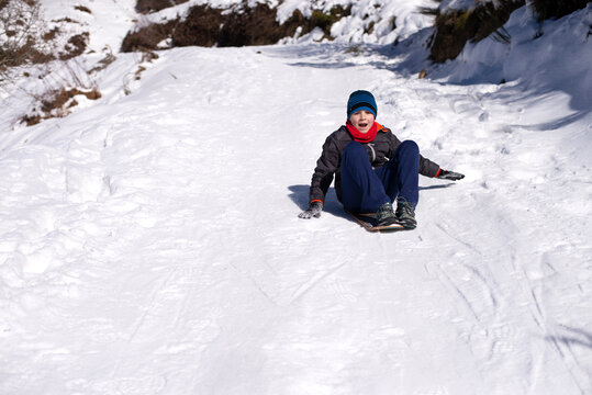 Boy slides down from the snow slope. Enjoying the winter sledding time