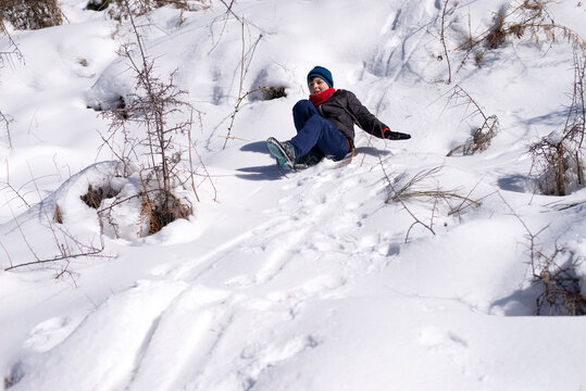 Boy slides down from the snow slope. Enjoying winter sledding time