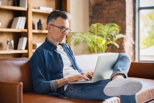 Caucasian mature middle-aged businessman freelancer journalist it specialist working remotely on laptop, communicating with clients customers at home office, watching webinars online