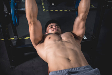 A fit asian man squeezing his pecs to get the extra pump while doing dumbbell bench presses....