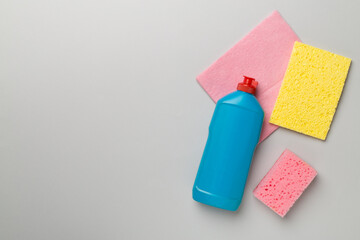 Bottle with dishwashing detergent and sponges on color background, top view