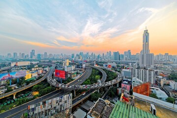 Panorama of Bangkok at dusk with skyscrapers in background and busy traffic on elevated expressways...