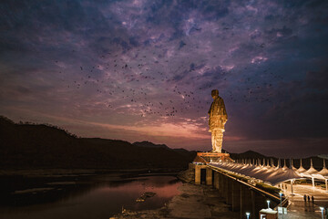 Beautiful shot of a statue of Unity in India against a cloudy sky at sunset