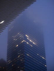 Vertical shot of the lights of a skyscraper in a fog - obrazy, fototapety, plakaty