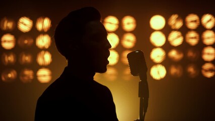 Silhouette singing man vocalist using microphone on show stage nightclub closeup - Powered by Adobe