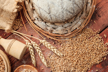 Round bread, wheat ears, white flour in a light wooden spoon. Concept agricultural, farm natural products, ingredients for baking, harvest. Import Export.
