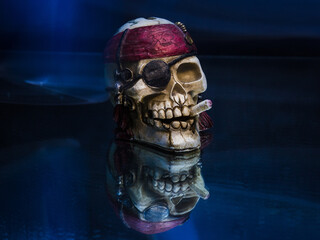 Shot of a pirate skull with cigarette and dark red bandana on a soft blue surface with reflection