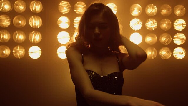Beautiful woman dancing sexually alone in night club spotlights.