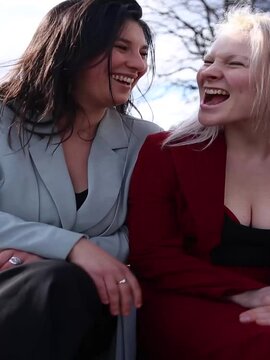 Lesbian couple sat together laughing.