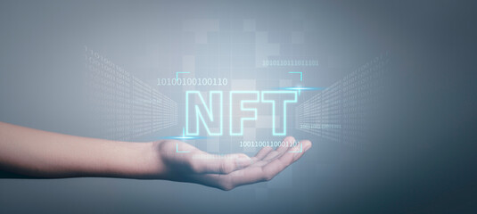 NFT non fungible tokens concept. Businessman holding digital unique art NFT text hologram on blue light