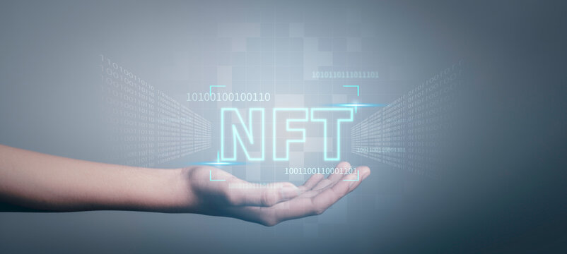 NFT non fungible tokens concept. Businessman holding digital unique art NFT text hologram on blue light