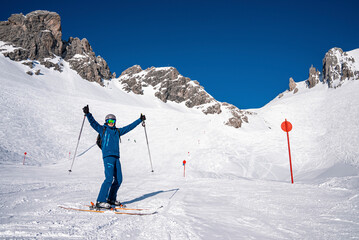 St. Anton am Arlberg. March 10, 2022. Young man in ski wear holding poles with arms outstretched...