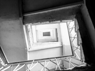 Overhead shot of a staircase on all floors of a building in grayscale