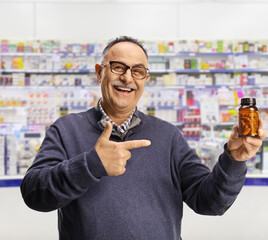 Mature man inside a pharmacy holding a bottle of pills