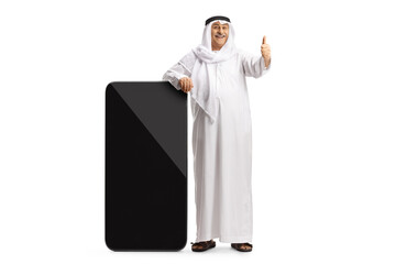 Mature arab man leaning on a big smartphone and showing thumbs up