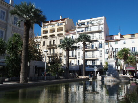 Pond, Palm trees and historical houses in Cannes, France, right the monument to lord brougham