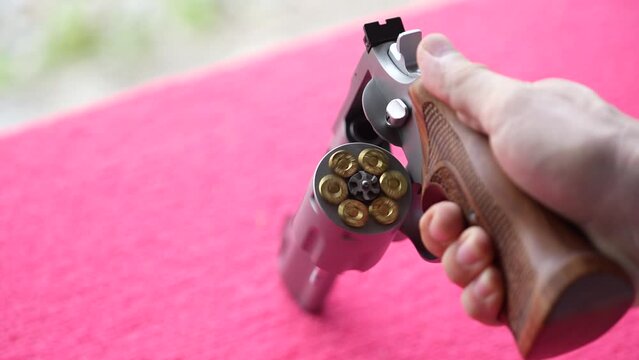 Revolver gun and bullets in hand man, close up. Revolver or wheel gun with a rotating cylinder and bullets inside