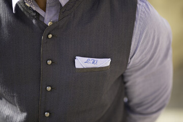 Closeup shot of the pocket square with initials on a groom's suit vest