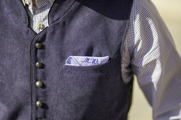 Closeup shot of the pocket square with initials on a groom's suit vest
