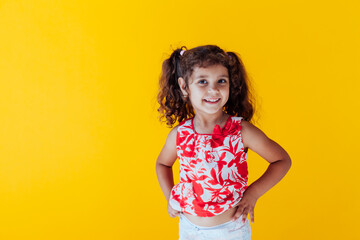 beautiful curly little girl with pigtails on yellow