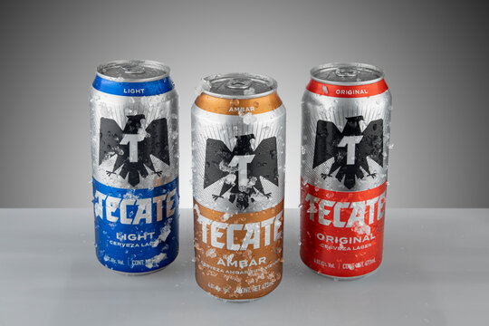Mexico ,CDMX - April 12, 2022: Canned Tecate of three different flavors, amber, red and light, frosted with ice and white background