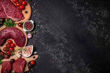 Variety of fresh raw beef steak with spices for grilling on a dark background. Whole piece of steaks ready to cook. banner, menu, recipe place for text, top view