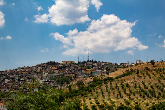 City of Irbid with buildings, houses and trees on hills under a cloudy sky