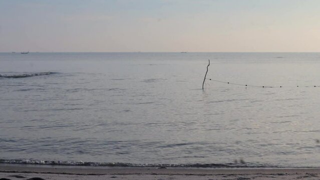 Gelombang laut menerjang di pantai pasir dalam warna oranye yang menakjubkan, matahari terbit pagi yang hangat di lanskap tepi laut dalam pemandangan yang stabil